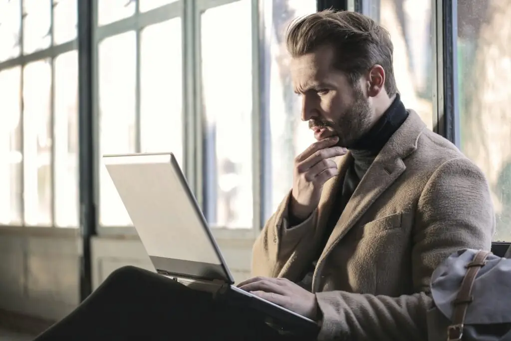 Hombre pensativo frente a su computadora portátil evaluando una decisión