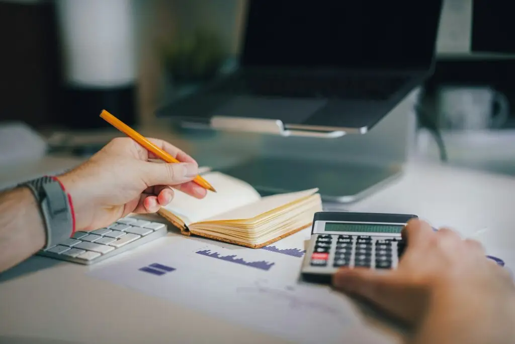 Persona haciendo cuentas con calculadora y cuaderno sobre un escritorio